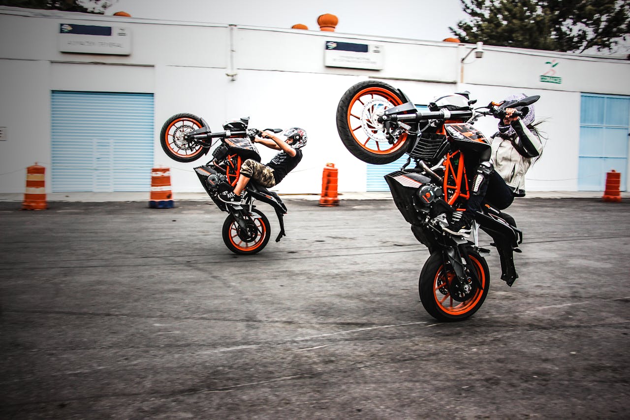 Two motorcyclists performing wheelies on a road in Mexico City, showcasing thrilling stunts.